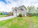 Side view of home with lawn, driveway and basketball hoop and fenced backyard at 807 Oak Manor Se Dr, Concord, NC 28025