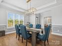 Elegant dining room with blue upholstered chairs, wood floors and modern light fixture at 811 Penny Royal Ave, Fort Mill, SC 29715
