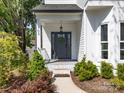 A welcoming front door with decorative wreath, sidelights, and manicured shrubs, creating curb appeal for the home at 103 Claremont Way, Mooresville, NC 28117