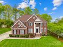 Beautiful two-story brick home with lush green lawn and mature trees on a sunny day at 130 Weeping Spring Dr, Mooresville, NC 28115