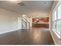 Open-concept living area with hardwood floors, a staircase, and natural light, adjacent to the kitchen at 4176 River Run Cir, Hickory, NC 28602