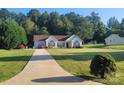 Expansive front lawn, complemented by a lush tree line, driveway and a charming single-story home with red shutters at 426 Summer Ridge Rd, Stanley, NC 28164