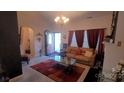 Cozy living room featuring a plush tan sofa, warm red curtains, and decorative glass table at 426 Summer Ridge Rd, Stanley, NC 28164
