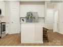 Bright kitchen featuring white cabinetry, stainless steel refrigerator, island with seating, and hardwood flooring at 4563 Potters Wheel Dr, Fort Mill, SC 29715
