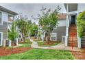 Exterior view of condo with a sidewalk surrounded by green grass, trees, and landscaping at 765 Southwest Dr, Davidson, NC 28036