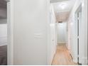Bright hallway with clean white walls and light wood-look flooring, illuminated by ceiling lights at 8322 Summerglen Cir, Charlotte, NC 28227