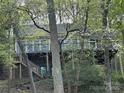 Wood home exterior with multiple windows and outdoor deck nestled among mature trees at 1224 Island Creek Dr, Troy, NC 27371