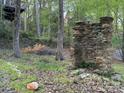 Stacked stone outdoor fireplace feature in wooded backyard of home at 1224 Island Creek Dr, Troy, NC 27371