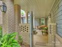 Inviting outdoor porch with brick pillars, lush greenery, and comfortable seating area at 2616 Colton Dr, Charlotte, NC 28211
