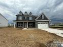 Charming two-story home with a covered porch and a two-car garage on a cloudy day at 3214 Mcharney Dr # 34, Harrisburg, NC 28075