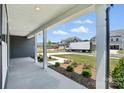 Covered porch with white pillars and manicured landscaping on a tree-lined street at 3214 Mcharney Dr # 34, Harrisburg, NC 28075