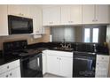 A well-lit kitchen featuring white cabinets, black appliances and granite countertops at 331 Eastwood Dr, Salisbury, NC 28146