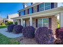Inviting front porch with brick facade and lush, purple bushes on a sunny day at 5716 Langwell Ln, Charlotte, NC 28278