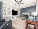 Comfortable living room with a fireplace, built-in shelving, stylish furniture, and a ceiling fan for optimal comfort at 653 Gable Oaks Nw Ln, Concord, NC 28027