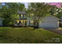Well-maintained two-story home with a lush front yard, porch, mature trees, and attached garage at 1694 Trotters Ridge Rd, Stanfield, NC 28163
