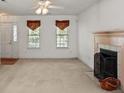 Bright living room features a ceiling fan, fireplace, two windows with decorative valances and neutral carpet at 1694 Trotters Ridge Rd, Stanfield, NC 28163