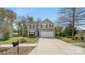 A spacious driveway leading to a two-story home featuring neutral siding and vibrant red shutters at 2120 Turtle Point Rd, Charlotte, NC 28262