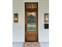 Close-up of a Craftsman-style front door with sidelights and a wreath, flanked by outdoor lighting fixtures at 2309 Pinckney Ave, Charlotte, NC 28205