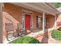 Charming brick home featuring a cozy front porch with rocking chairs and a welcoming red door at 255 Fernbrook Dr, Mooresville, NC 28117