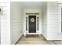 Close-up of the front door with a wreath, decorative rug, sidelights, and white siding at 3081 Montreaux Valley Dr, Fort Mill, SC 29707