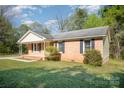 Quaint brick home featuring dark shutters, a cozy front porch, and a well-maintained front lawn at 700 Fine Wright Ave, York, SC 29745