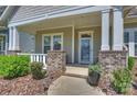 Inviting front porch featuring decorative brick columns, potted plants, and a charming front door at 10378 Ambercrest Nw Ct, Huntersville, NC 28078