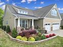 Inviting home exterior featuring a covered porch, stone accents, and beautifully landscaped garden beds at 1497 Tranquility Blvd # 417, Lancaster, SC 29720