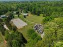Aerial view of the property showcasing the house, barn, riding ring, and lush surrounding landscape at 228 Red Dog Dr, Mooresville, NC 28115