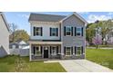 Charming two-story home features gray siding, black shutters, a covered porch, and a well-maintained front yard at 3804 Freedom Dr, Charlotte, NC 28208