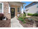 Cozy front porch with decorative floral wreath and potted plants with stone and siding exterior at 8524 Sunset Hill Rd, Waxhaw, NC 28173