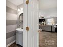 Stylish half-bathroom featuring a modern sink, round mirror, and eye-catching striped wallpaper design at 8604 Cedardale Ridge Ct, Charlotte, NC 28269