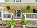 Charming front porch with brick steps, potted ferns, and white railing, leading to the front door at 915 Gate Rd, Monroe, NC 28112