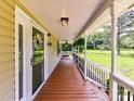 Covered front porch with wood flooring and black railing, offering a view of the green yard at 915 Gate Rd, Monroe, NC 28112