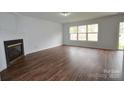 Inviting living room with wood-look floors, a fireplace, and large windows for ample light at 14608 Arlandes Dr, Charlotte, NC 28278