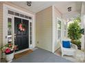 Inviting front porch with a black door, wreath, welcome mat, and wicker chair at 19416 Fridley Ln, Cornelius, NC 28031