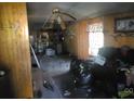 Damaged interior view shows water damage, wood paneling, debris, and discarded items throughout the property interior at 2702 W Stage Coach Trl, Shelby, NC 28150