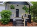 Inviting front porch with black accents and wooden railings, adorned with hanging ferns for curb appeal at 409 N Apple St, Gastonia, NC 28054