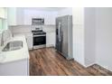 Modern kitchen with white cabinetry, stainless steel appliances, subway tile backsplash, and wood grain flooring at 409 N Apple St, Gastonia, NC 28054
