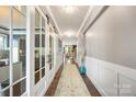 Elegant hallway with hardwood floors, paneled walls, stylish lighting, and glass doors at 487 Hawks Creek Pkwy, Fort Mill, SC 29708