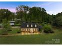 Nighttime view of a house with a well-manicured front lawn and mature trees at 4896 Pageland Hwy, Lancaster, SC 29720