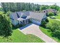 An aerial view of a well-maintained home with lush green landscaping, a spacious driveway, and a charming front porch at 557 Luther Dr, Iron Station, NC 28080