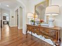 Elegant hallway featuring hardwood floors, neutral walls, decorative mirror, and stylish lamps at 7208 Ashton Gate Dr, Charlotte, NC 28270