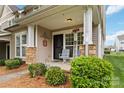 Inviting porch featuring stone accents, welcome decor, seating, and manicured landscaping, offering a cozy entrance at 1013 Laparc Ln, Indian Trail, NC 28079