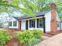 Charming home with white siding, brick chimney, and black shutters surrounded by green foliage and natural landscaping at 11817 Five Cedars Rd, Charlotte, NC 28226