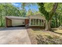 Exterior view of a brick house, driveway on left, covered and screened porch, and mature tree at 1444 Harris St, Statesville, NC 28677