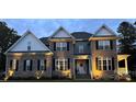 Charming two-story brick home featuring a welcoming front porch and tasteful landscaping with blooming flowers at 3011 Waxhaw Crossing Dr, Waxhaw, NC 28173