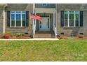 Home's entryway with American flag, brick stairs and black shuttered windows at 3011 Waxhaw Crossing Dr, Waxhaw, NC 28173