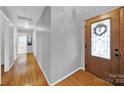 Inviting hallway features hardwood floors and a decorative front door with glass panes at 7410 Middlebury Pl, Charlotte, NC 28212