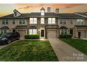 Charming townhouse showcasing a stone facade, two-car garage, and well-manicured lawn at sunset at 9618 Springholm Dr, Charlotte, NC 28278