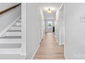 Bright hallway with hardwood floors, white walls, leading to living area and stairs at 10942 Winterbourne Ct, Charlotte, NC 28277